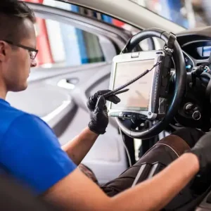 A technician performing a safety systems recalibration on a vehicle using advanced diagnostic equipment.